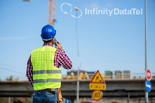 Construction worker staring off at the sky while on the phone.