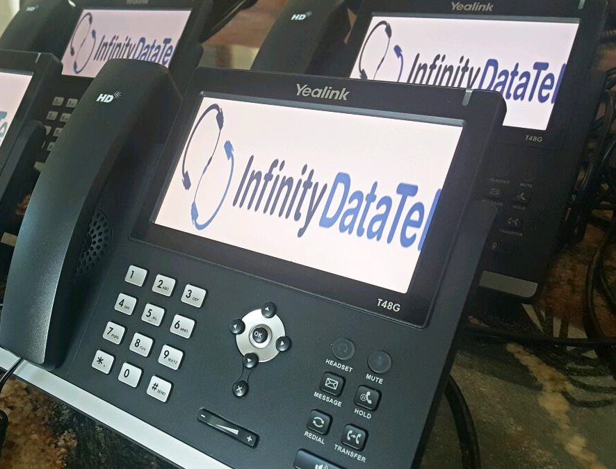 A Yealink VoIP phone system sit on a conference table