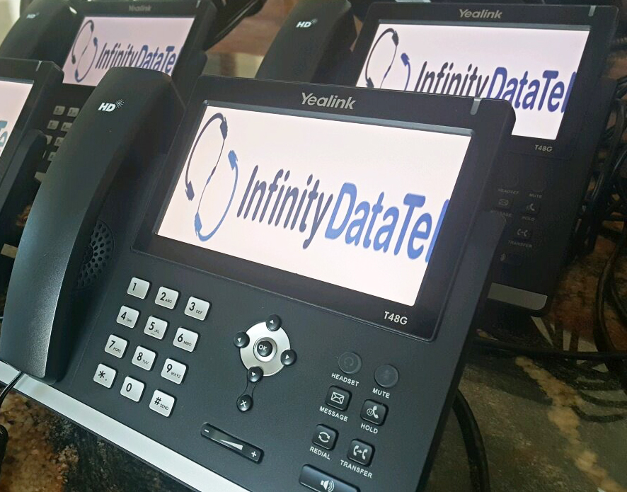 A Yealink VoIP phone system sit on a conference table