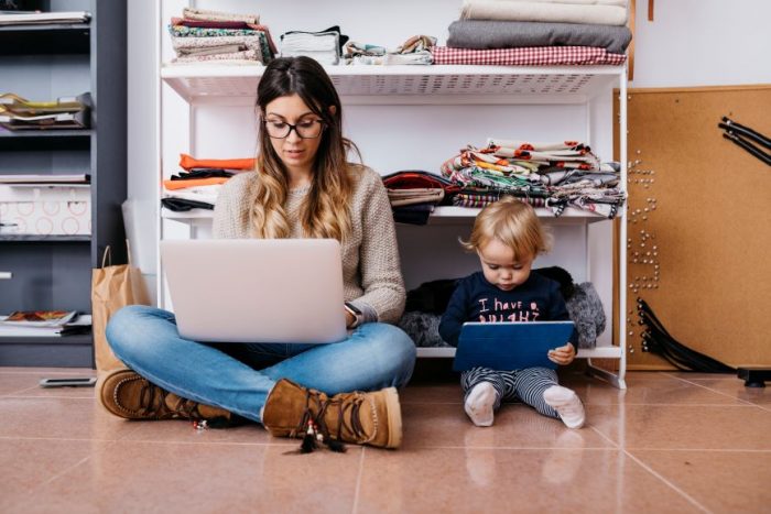 This woman is doing some remote work with her small child.
